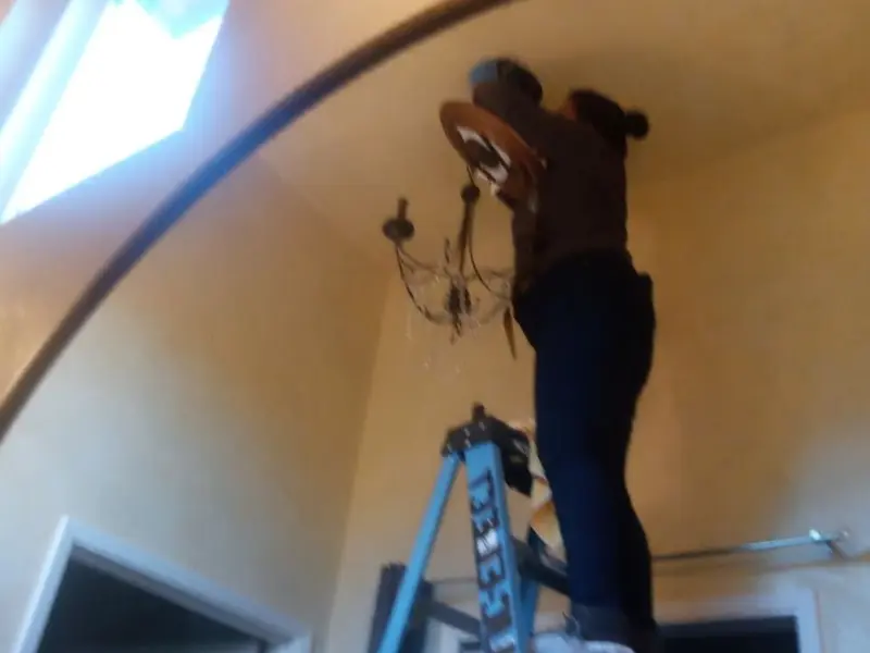 Electrician installing a chandelier in a Lake Zurich residence